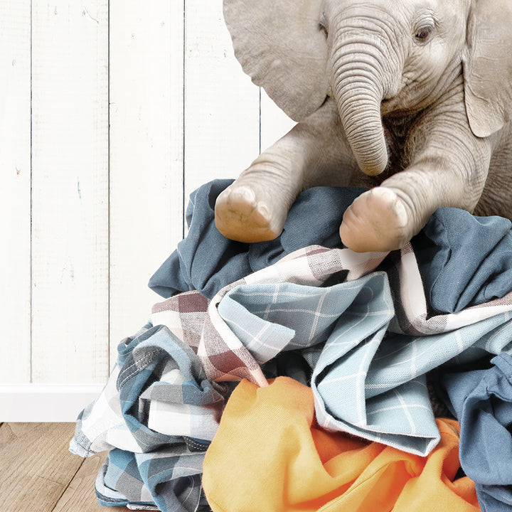 a stuffed elephant sitting on top of a pile of clothes