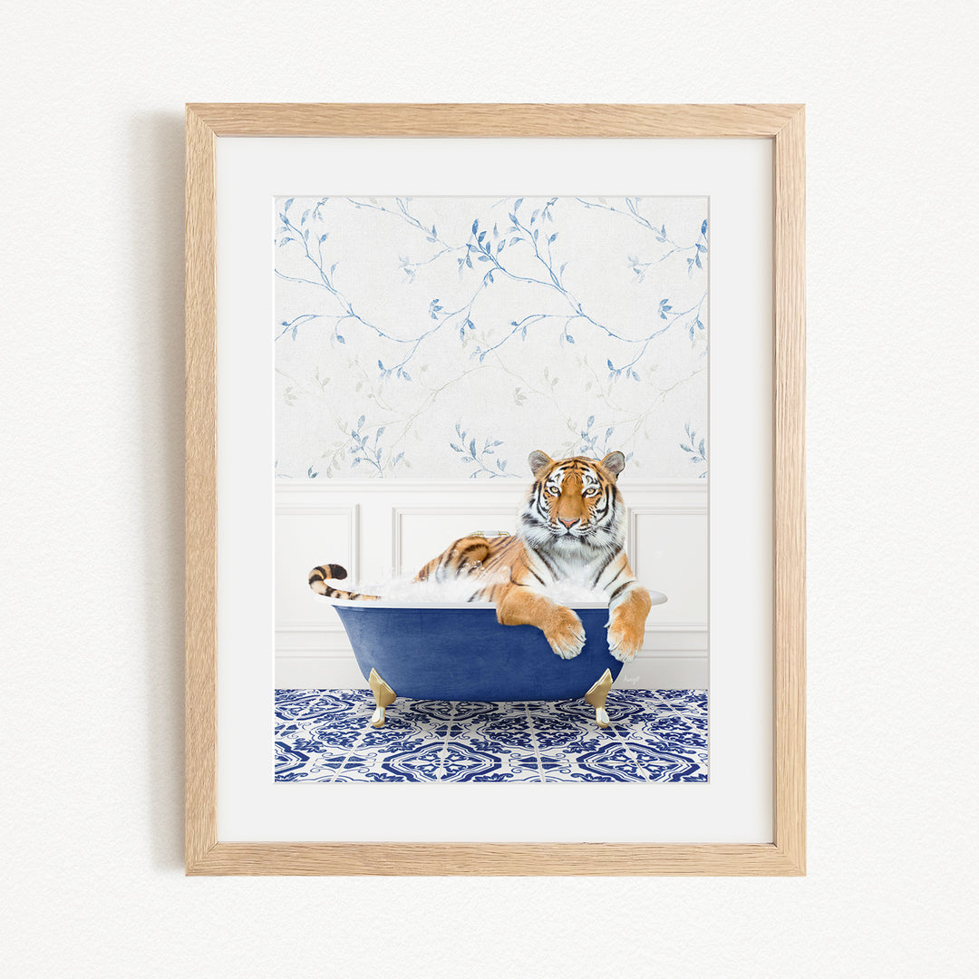 A tiger is sitting in a blue bathtub, surrounded by a blue and white patterned wall and a white floor.
