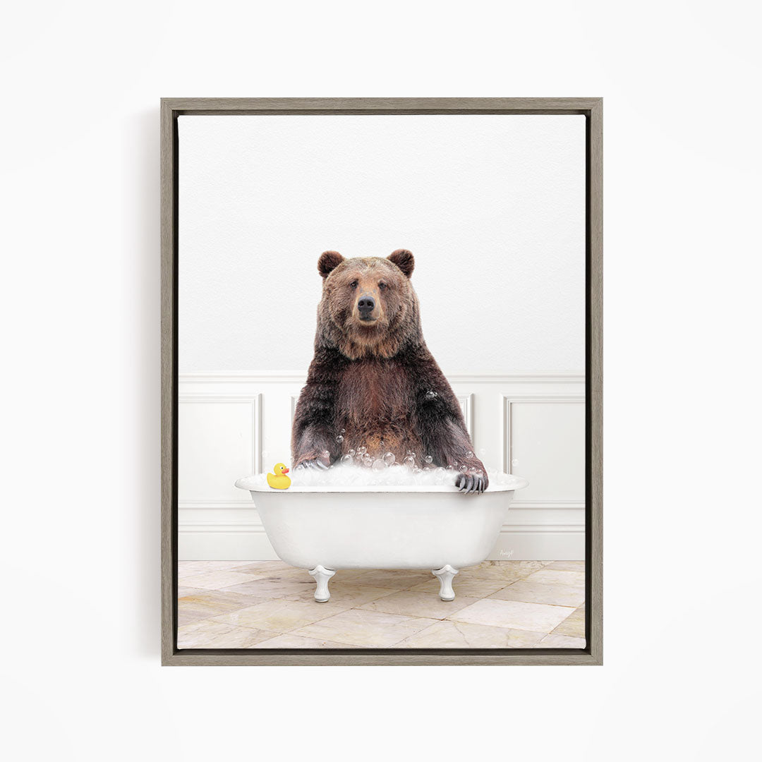 A brown bear sitting in a white bathtub, with a yellow rubber duck floating on the water.