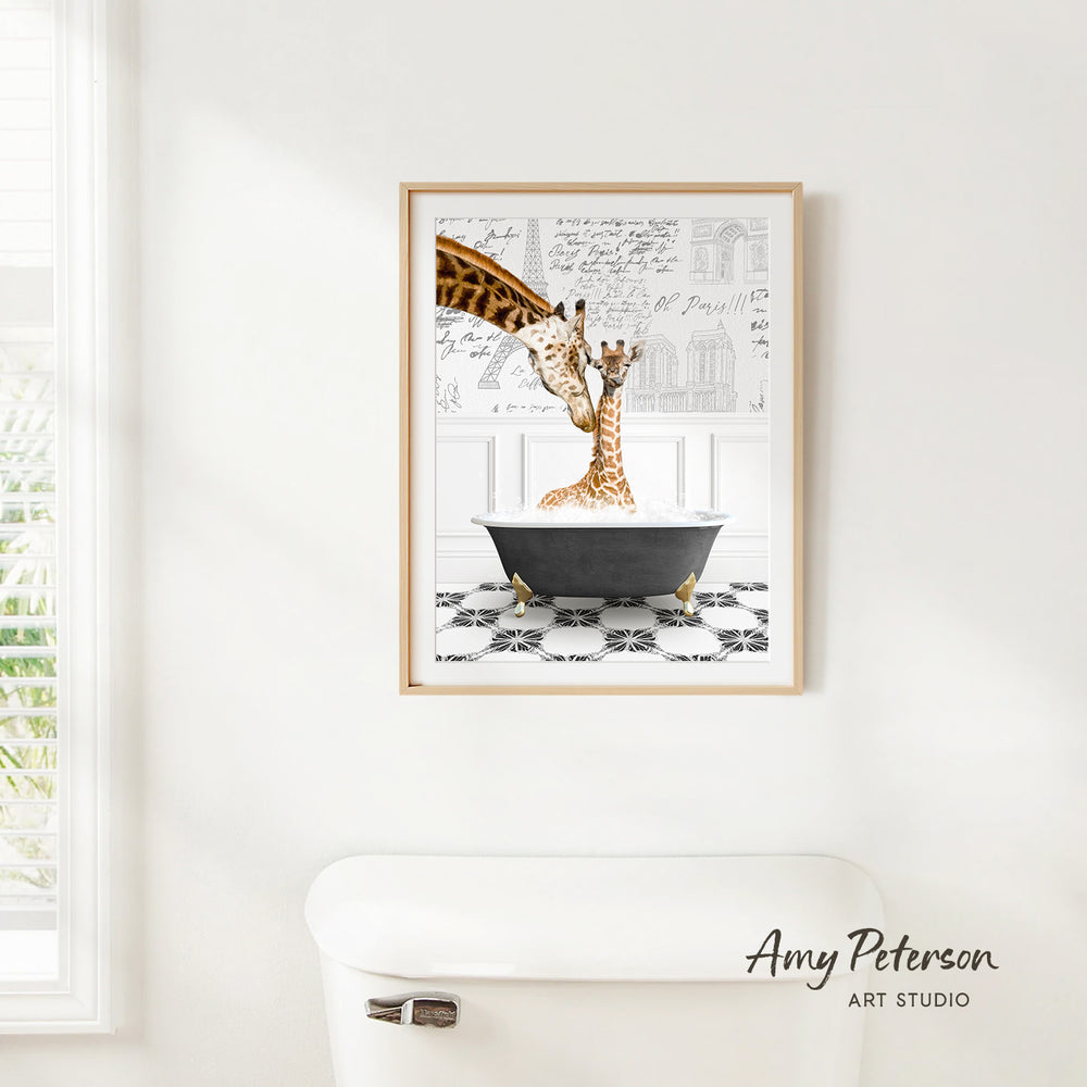 A framed print of two giraffes sitting in a bathtub is hanging on a white wall.