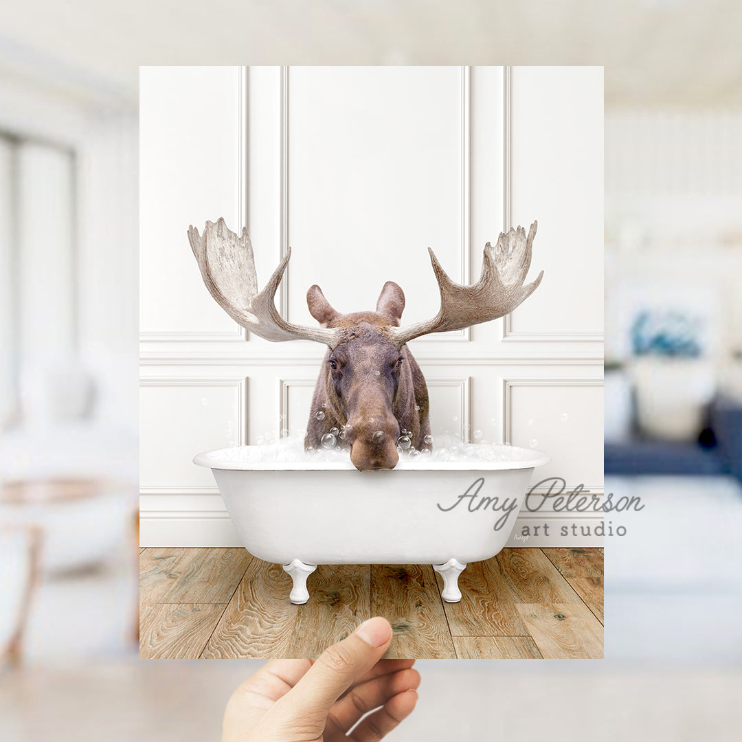 a hand holding a photo of a moose in a bathtub