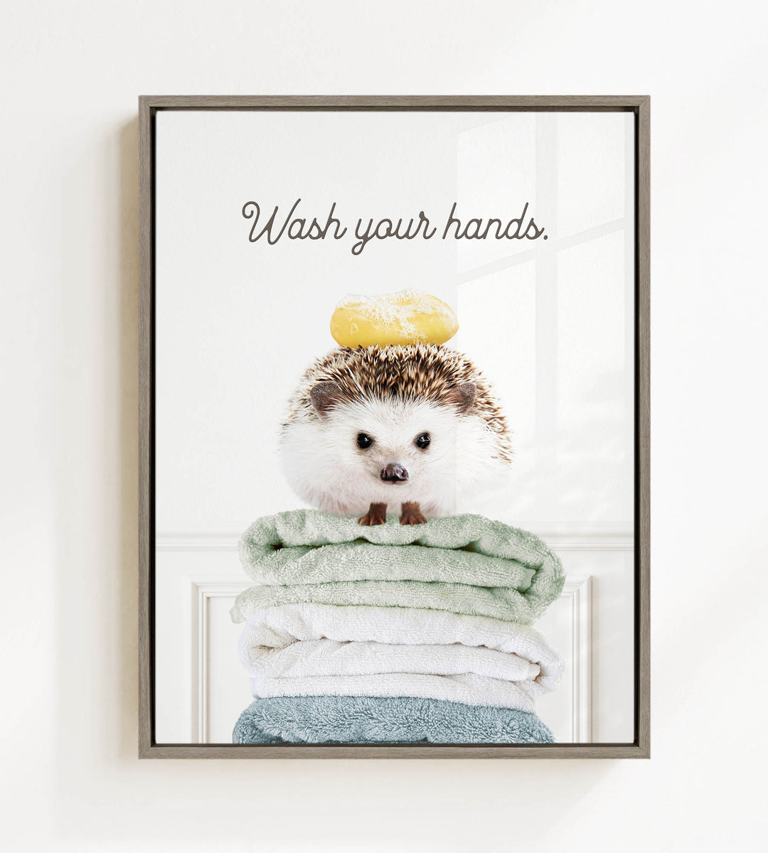 A cute hedgehog sitting on a stack of folded towels, with the text "Wash your hands" written above it.