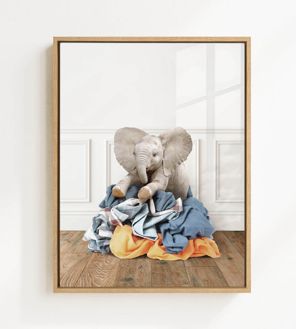 A baby elephant sitting on a pile of clothes in a room.