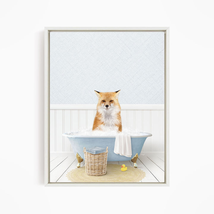 A red fox is sitting in a blue bathtub filled with bubbles, surrounded by a yellow rubber duck and a white basket.