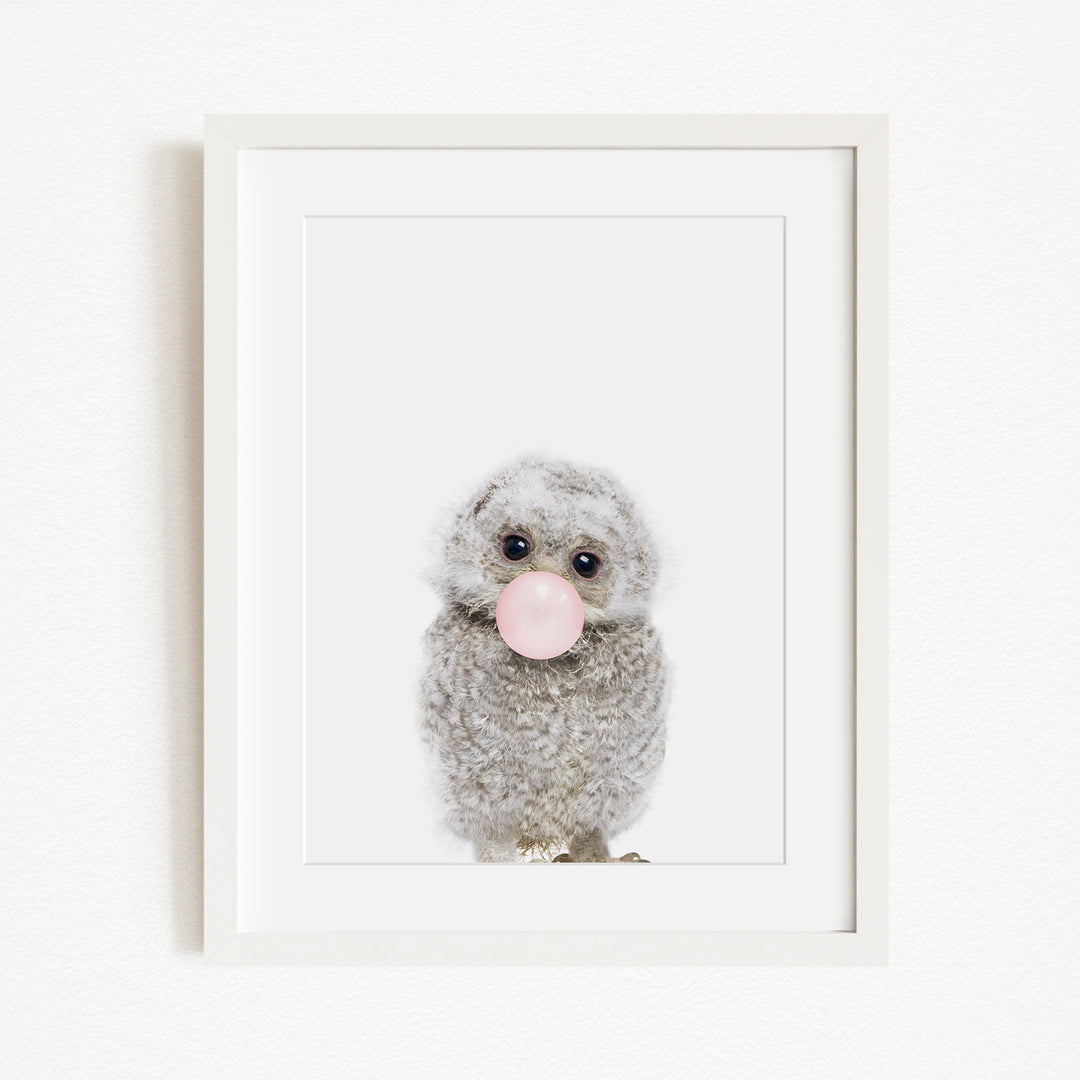 A cute gray owl with large eyes is blowing a bubble with a pink bubble gum bubble wand.