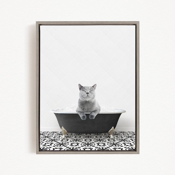 A gray cat sitting in a black bathtub filled with bubbles, with a black and white patterned floor beneath it.