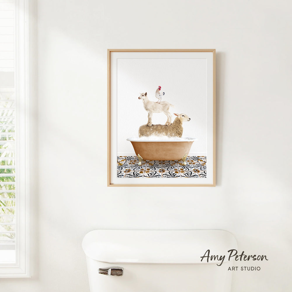 A framed image of a sheep standing on a bathtub, with a rooster perched on top, is hanging on a white wall.