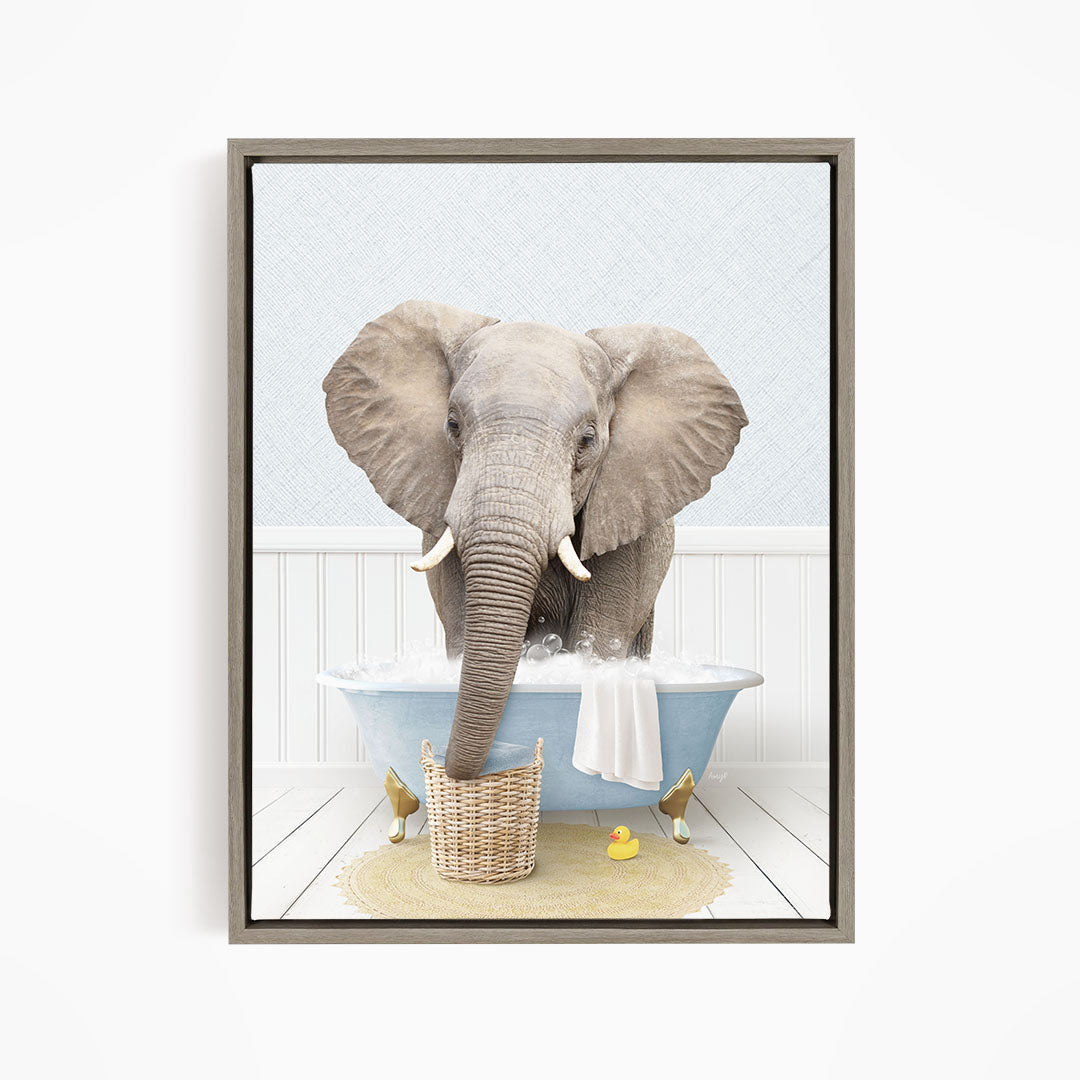 A gray elephant is standing in a blue bathtub filled with water, surrounded by a yellow rubber duck and a basket.
