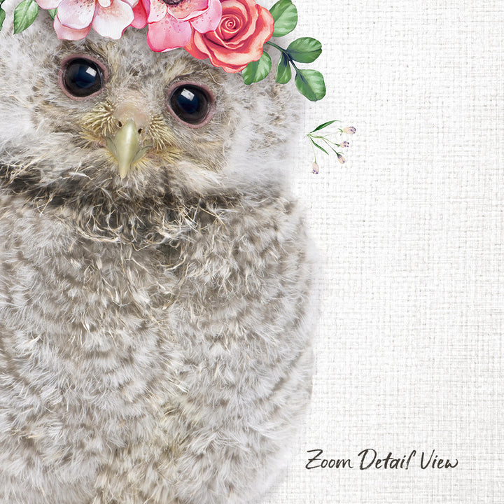 A close-up of a fluffy gray owl wearing a floral crown of pink and red flowers, with its eyes gently closed.