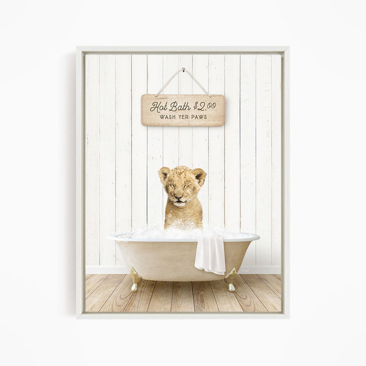A young lion cub sitting in a bathtub, with a sign above it that reads "Hot Bath $2.00 WASH YOUR Paws".