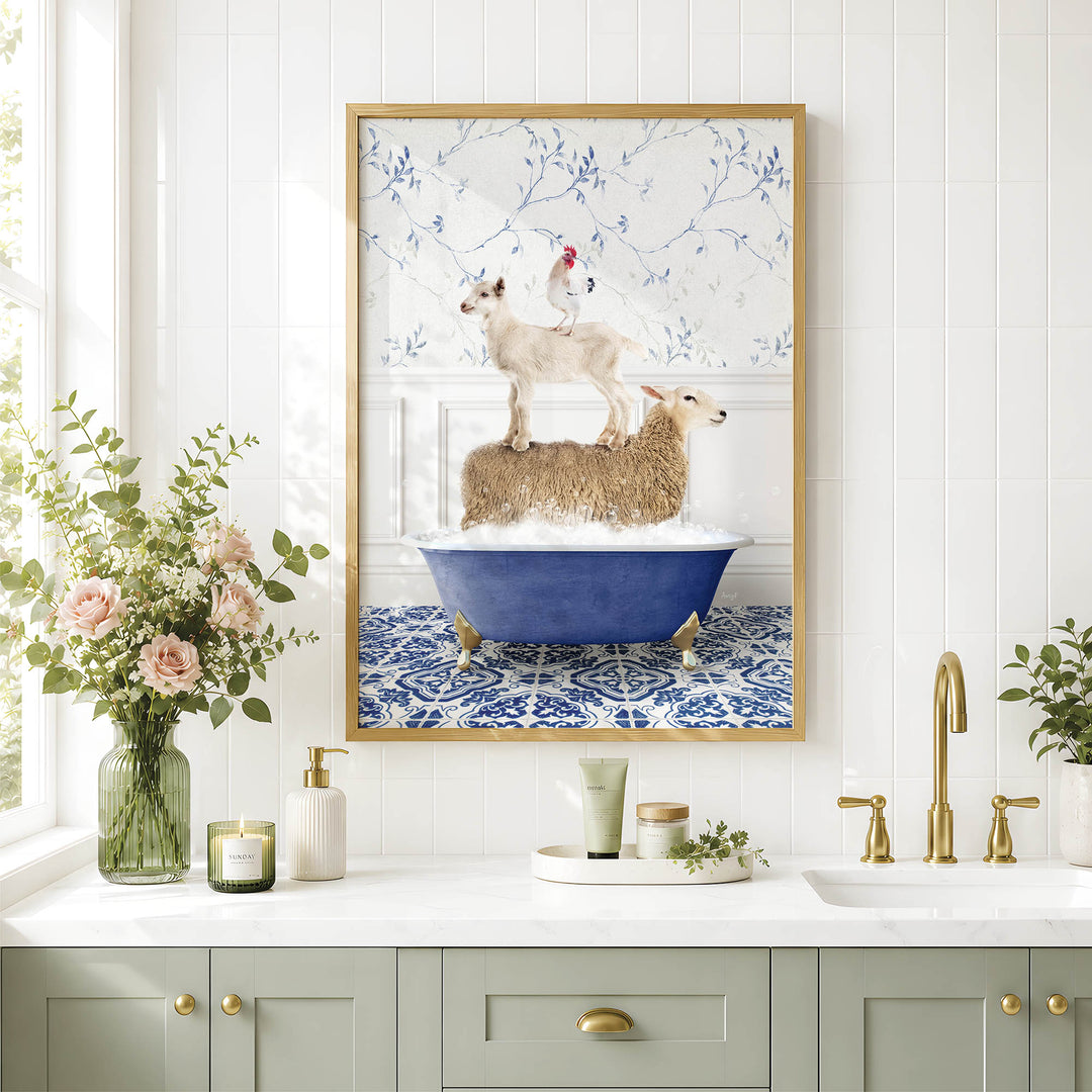 A framed image of a sheep standing on a bathtub, with a chicken perched on top, is displayed on a white tiled wall above a bathroom counter with various toiletries and a vase of flowers.