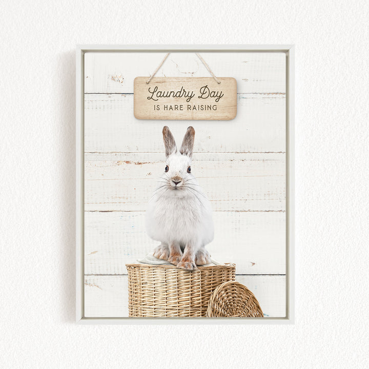 A white rabbit sitting on a wicker basket, with a wooden sign above that says "Laundry Day is HARE RAISING".