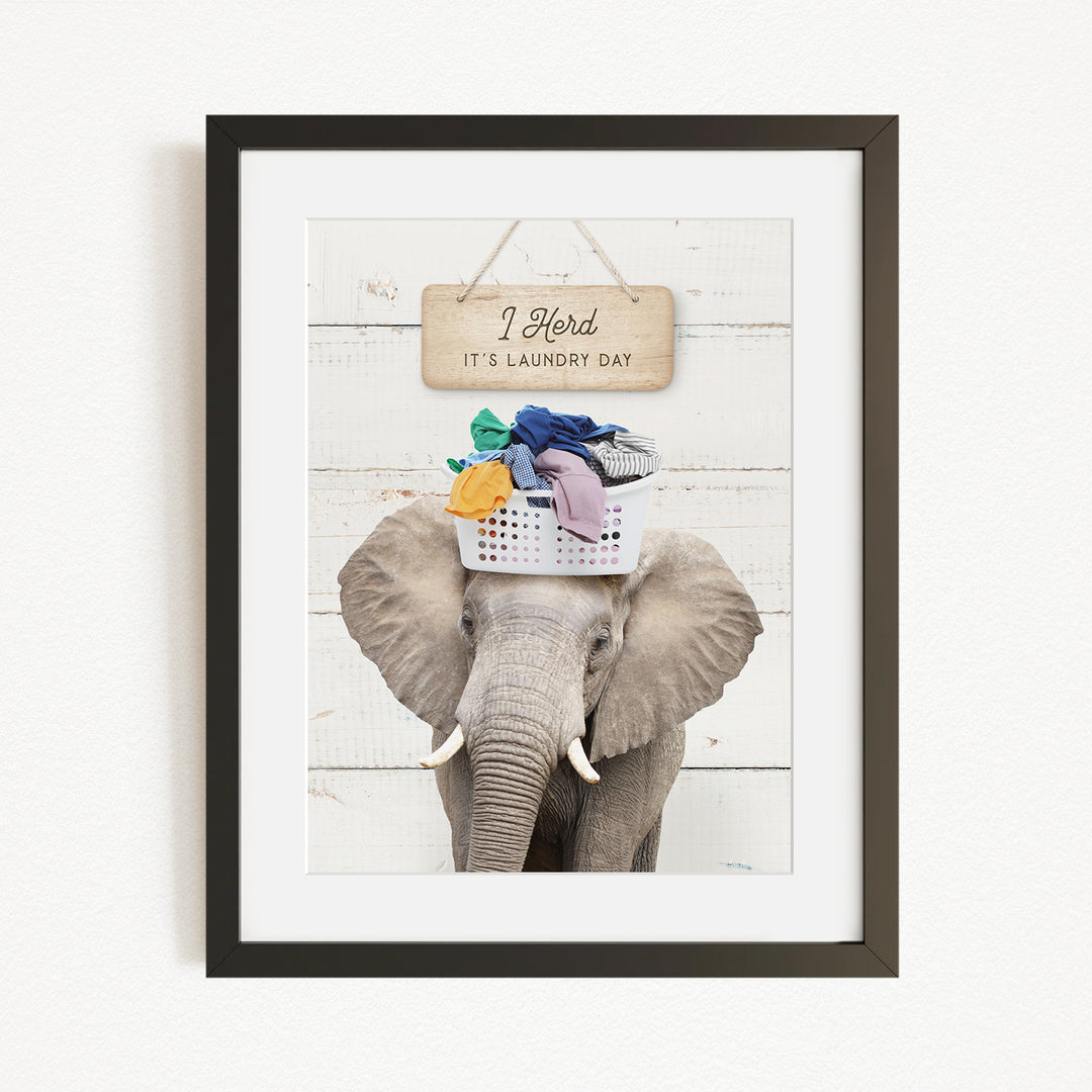 A framed image of an elephant holding a basket of laundry, with a sign above it that says "I Harded It's Laundry Day".