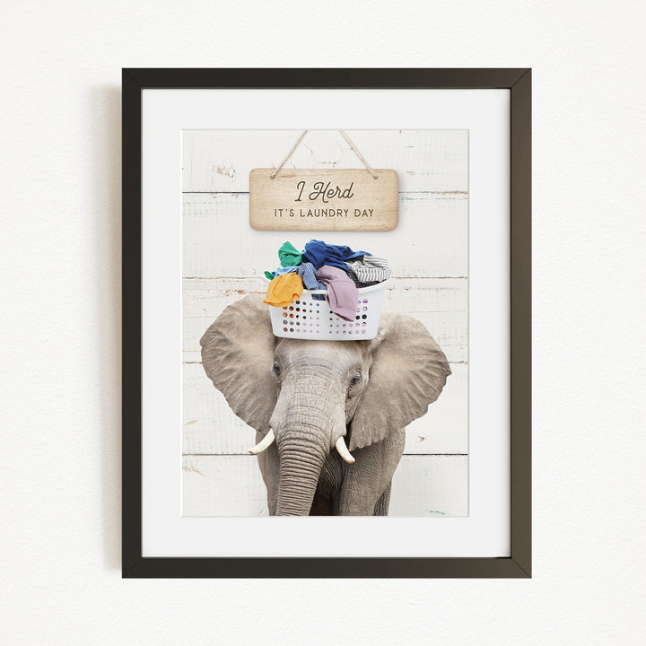 A framed image of an elephant holding a basket of laundry, with a sign above it that says "I Harded It's Laundry Day".
