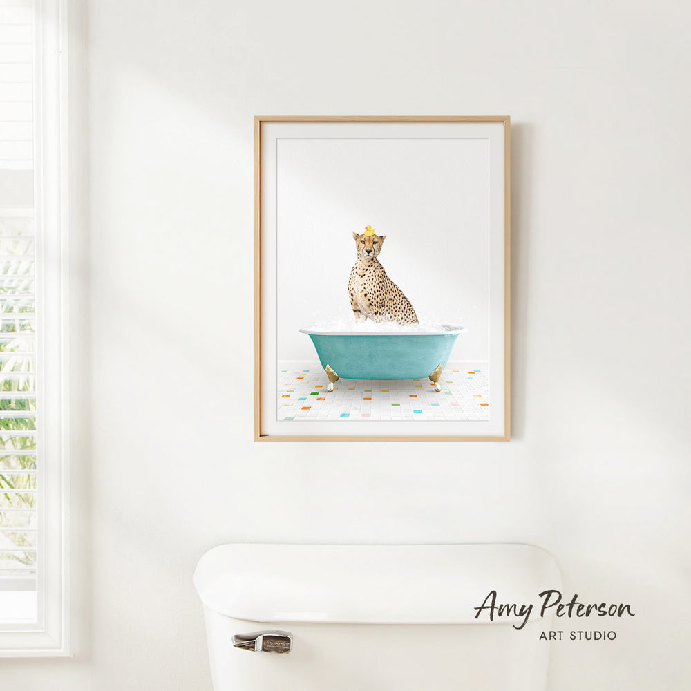 A cheetah sitting in a blue bathtub, wearing a yellow crown, is the central focus of the framed artwork displayed on a white wall.