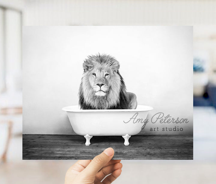 a hand holding up a black and white photo of a lion in a bathtub