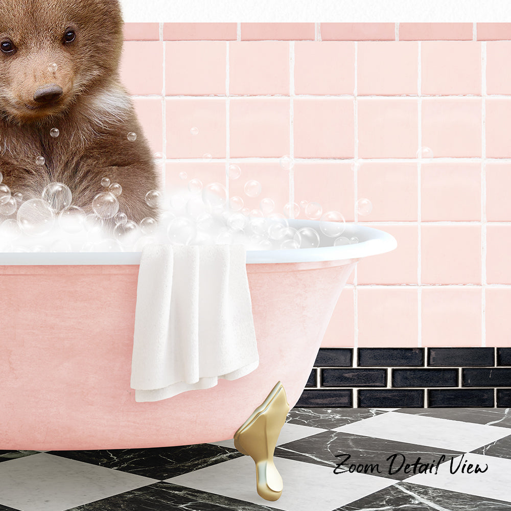 A brown bear sitting in a pink bathtub filled with bubbles, with a towel hanging on the side and a pink tile wall in the background.