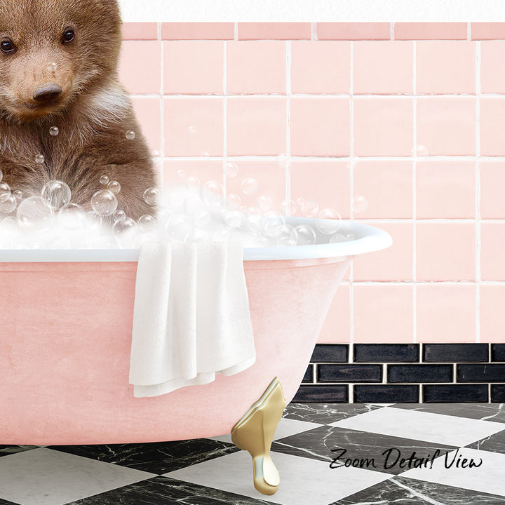 A brown bear sitting in a pink bathtub filled with bubbles, with a towel hanging on the side and a pink tile wall in the background.