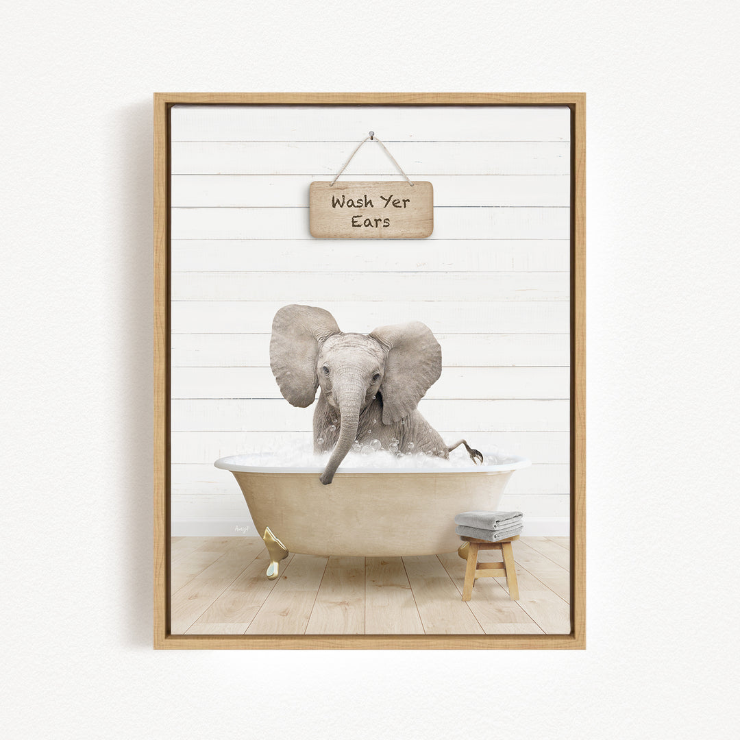 A framed image depicting an elephant sitting in a bathtub, with a sign above that reads "Wash Your Ears".