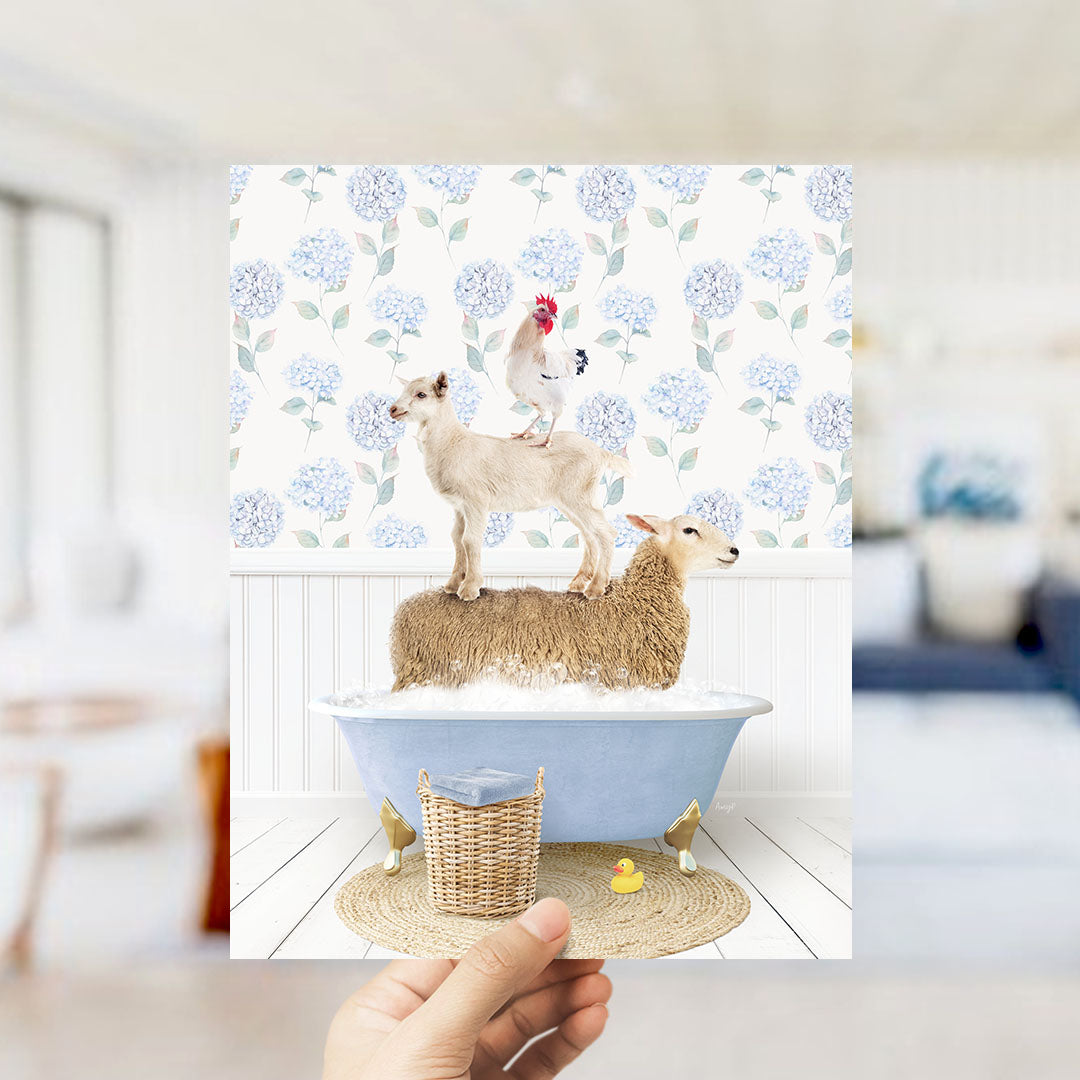 A hand holds up a framed image depicting a goat standing on a sheep's back while both animals are in a blue bathtub filled with bubbles.