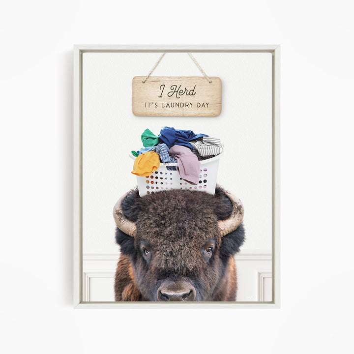 A buffalo with a basket of laundry on its head, accompanied by a wooden sign that says "It's laundry day".