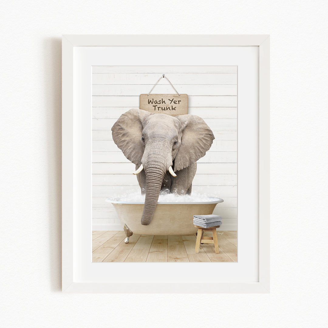 A framed image of an elephant standing in a bathtub, with a sign above it that says "Wash Yer Trunk".
