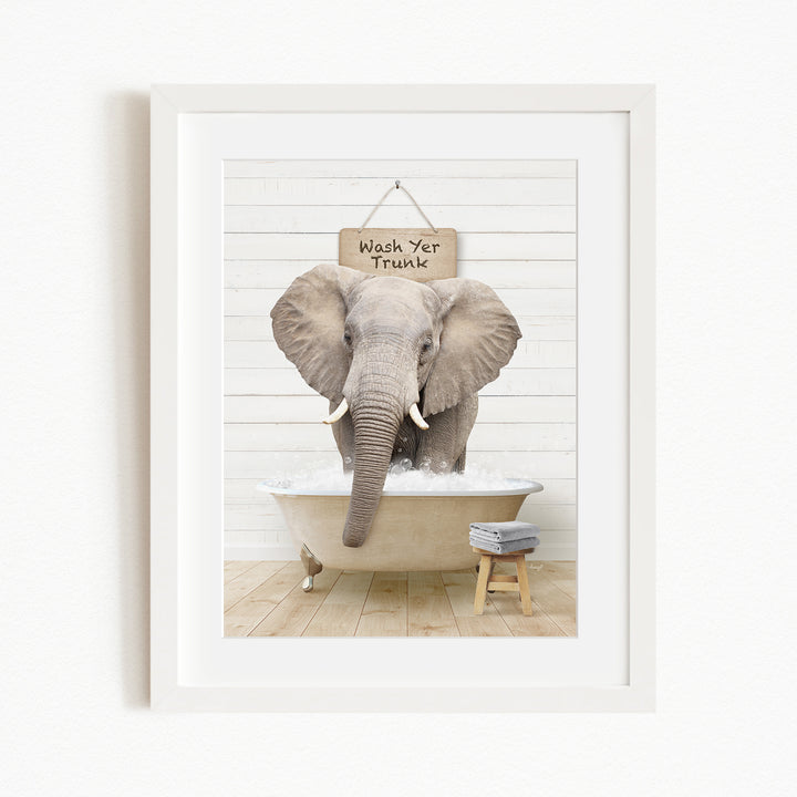 A framed image of an elephant standing in a bathtub, with a sign above it that says "Wash Yer Trunk".