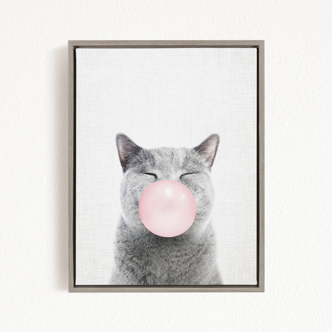 A gray cat with its eyes closed and a pink bubble blowing in its mouth.
