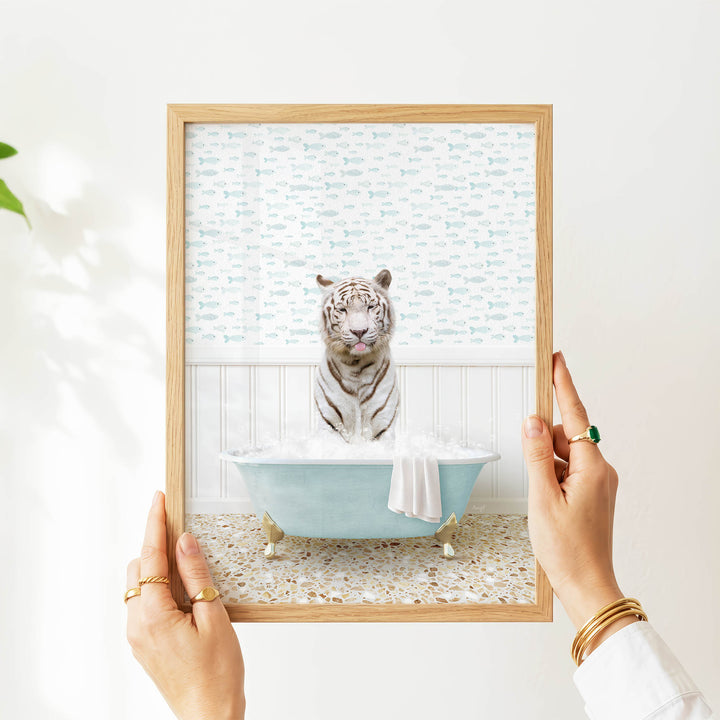 A person's hands are holding a framed image of a tiger sitting in a bathtub filled with water and bubbles.