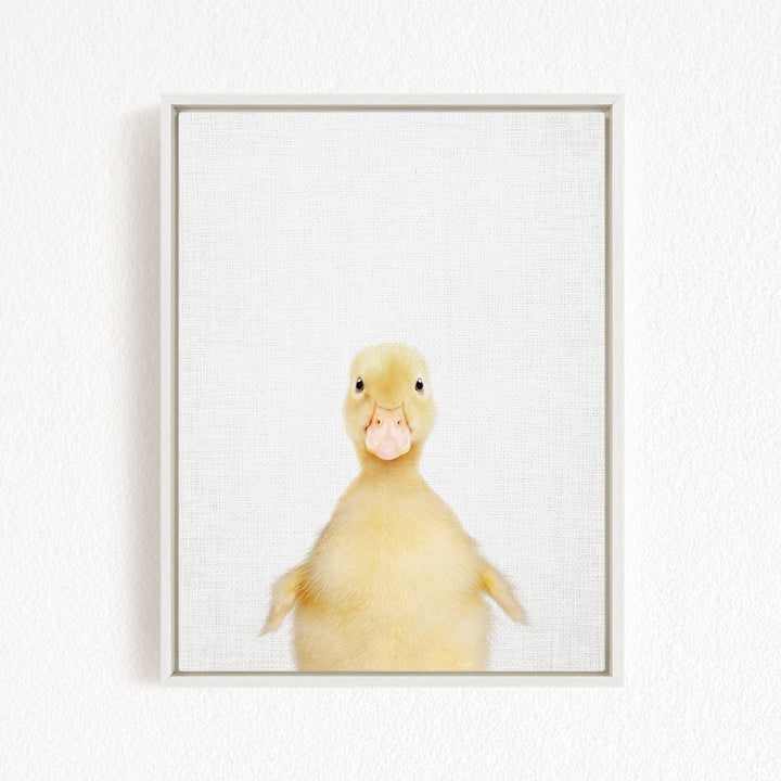 A cute yellow duck with a pink beak is standing in a white frame against a plain white background.