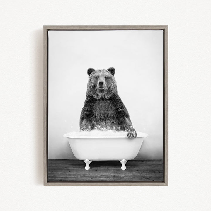 A black and white image of a bear sitting in a bathtub filled with bubbles.