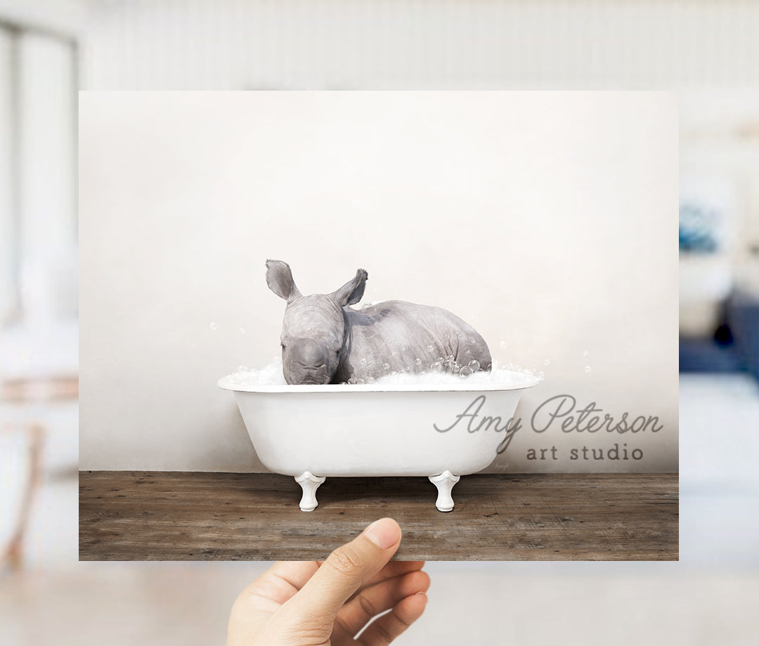 a hand holding up a card with a rhino in a bathtub