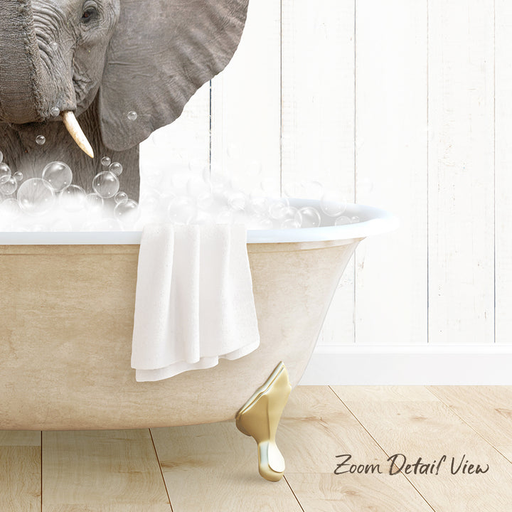 A large elephant is sitting in a bathtub filled with bubbles, with a towel draped over the side of the tub.