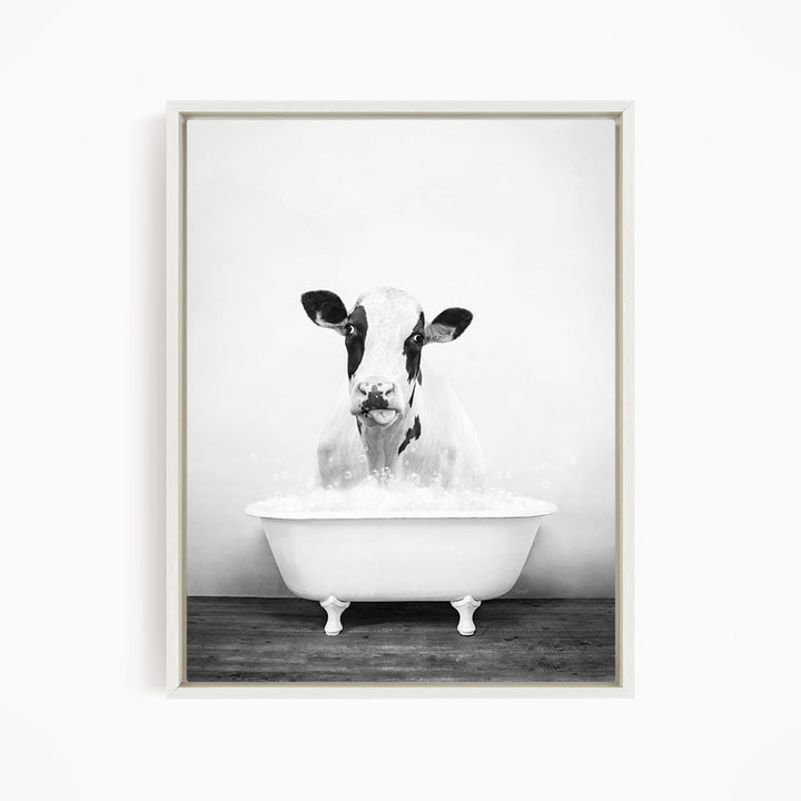A black and white image of a cow standing in a bathtub filled with water, looking directly at the camera.