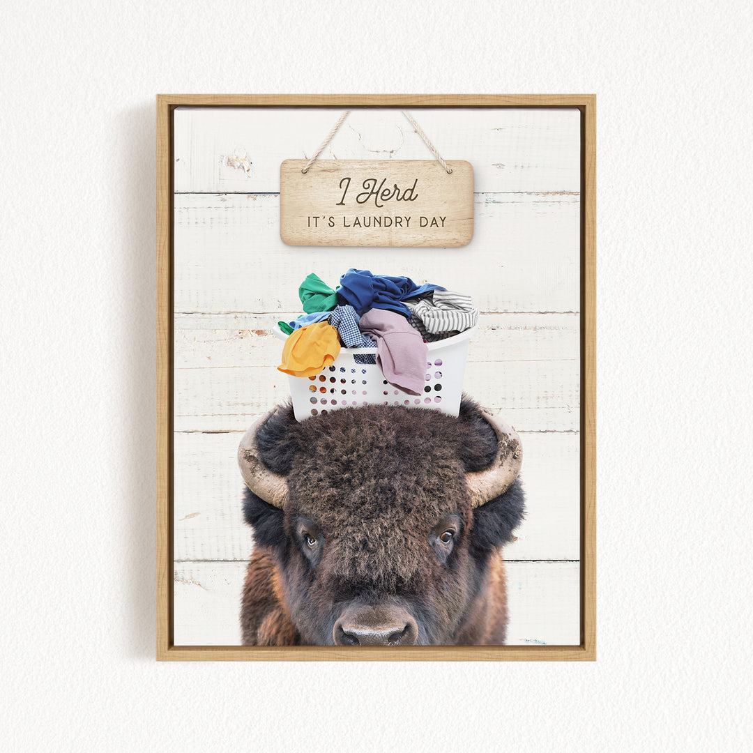 A framed image of a bison with a basket of laundry on its head, accompanied by a wooden sign that says "It's laundry day".