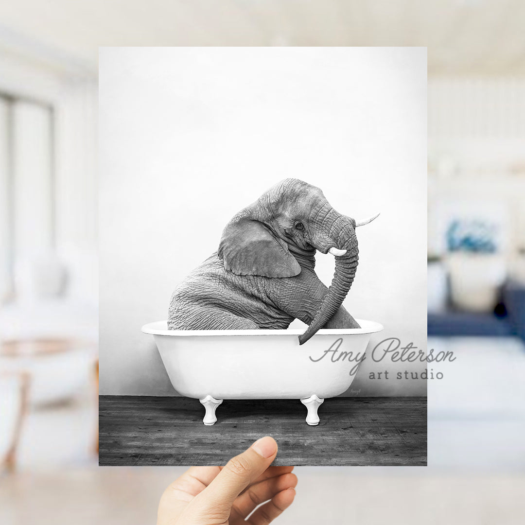 a hand holding up a black and white photo of an elephant in a bathtub