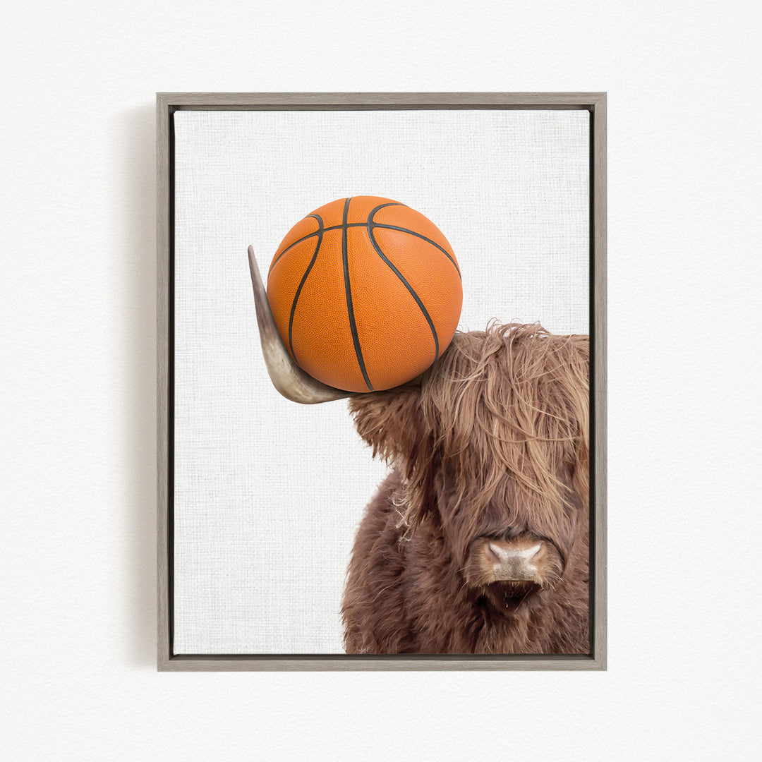 A brown cow with long hair is holding a basketball on its head.