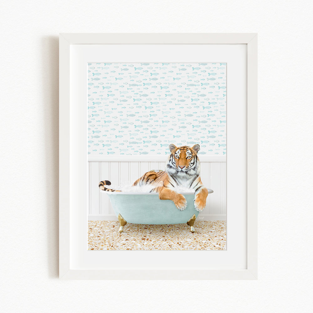 A tiger is sitting in a light blue bathtub, surrounded by a patterned wall and a tiled floor.