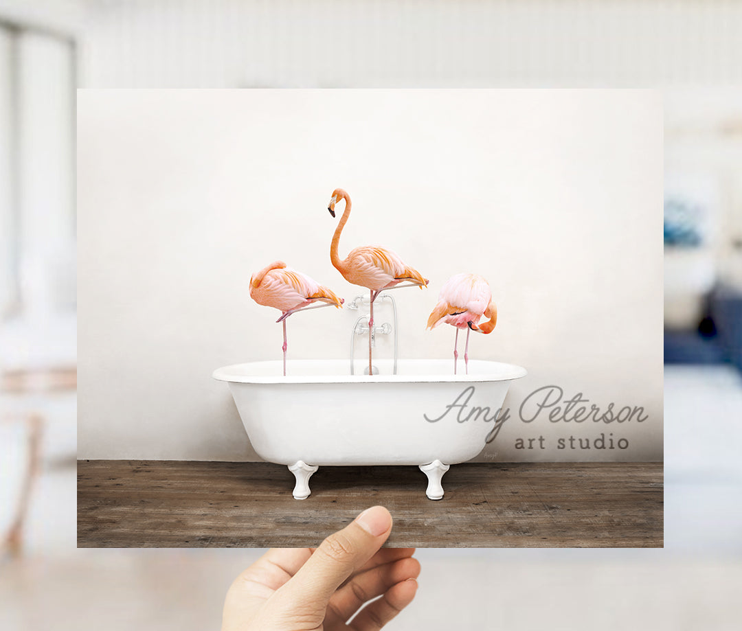 a person holding up a card with flamingos in a bathtub