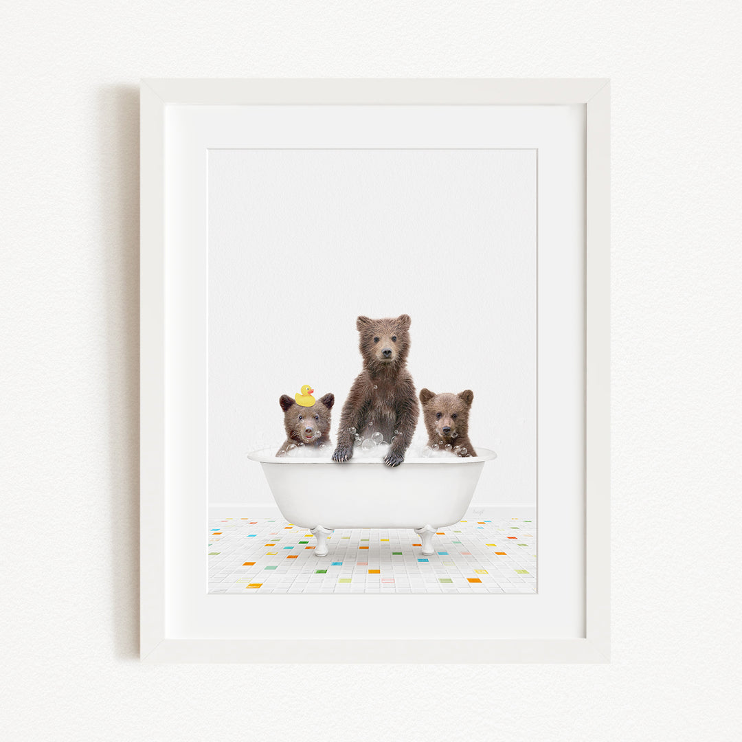 A framed image depicting three bears sitting in a white bathtub, with one bear wearing a yellow hat.
