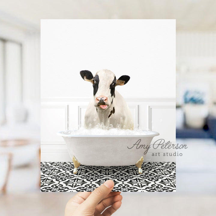 a hand holding up a picture of a cow in a bathtub