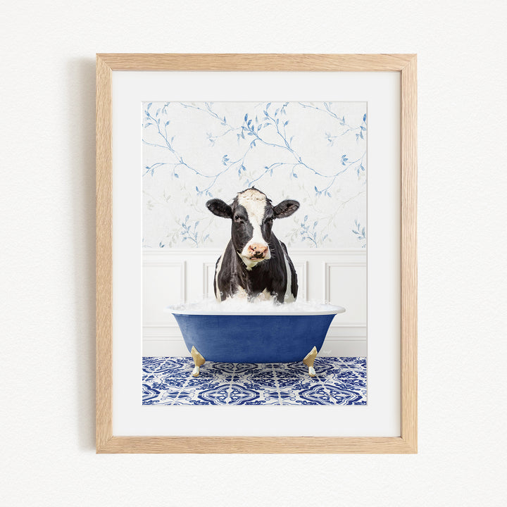 A black and white cow is sitting in a blue bathtub filled with water, creating a whimsical and humorous scene.