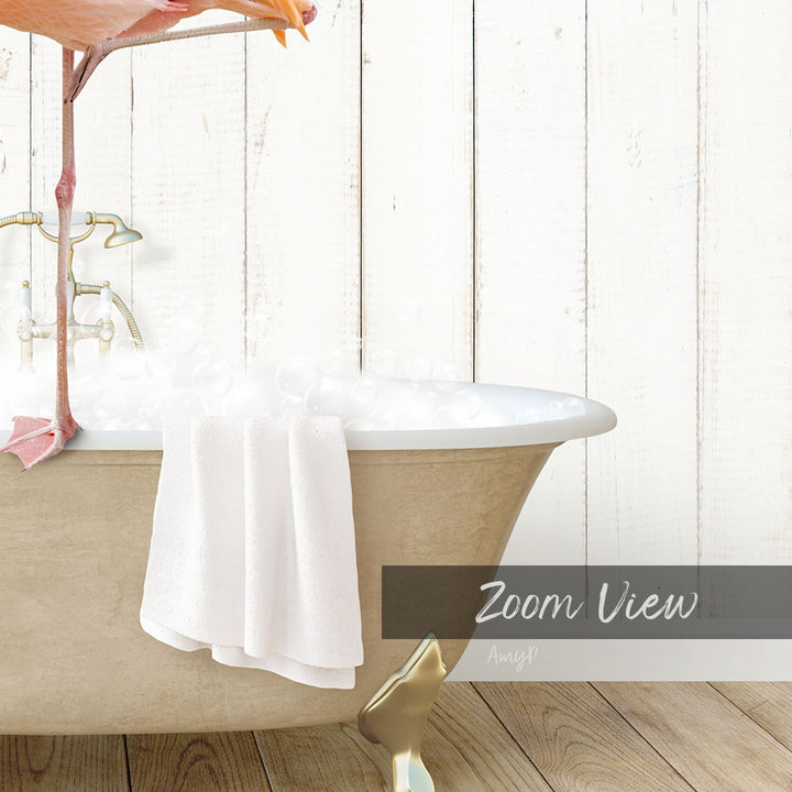 A white claw-foot bathtub filled with water and a white towel, with a pink flamingo perched on the edge of the tub.