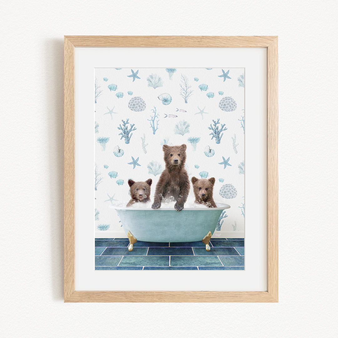 A framed image depicting three brown bears sitting in a bathtub filled with water, surrounded by a blue and white ocean-themed wallpaper.