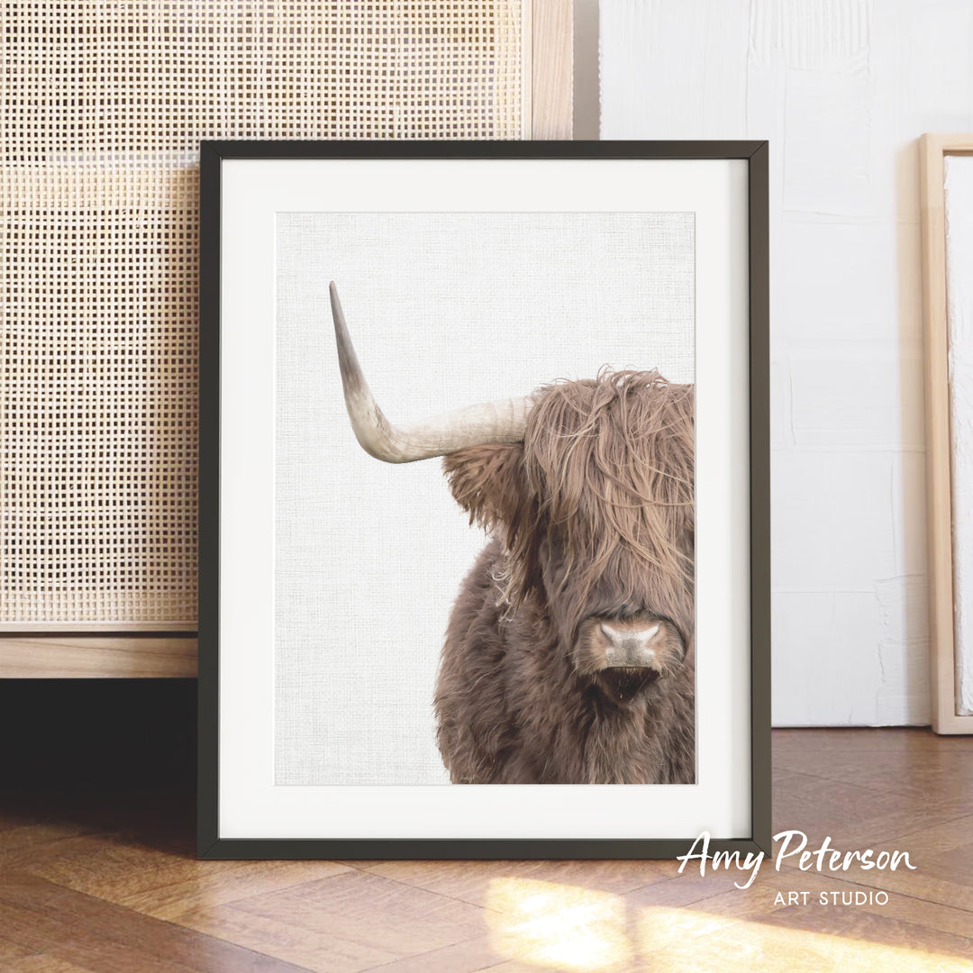 A framed image of a shaggy-haired, horned animal, likely a yak or a similar species, is displayed in a wooden frame on a wooden floor.