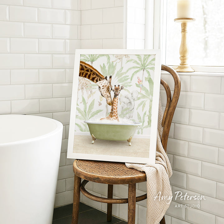 A framed image of two giraffes sitting in a bathtub, surrounded by a tropical plant backdrop, is displayed on a wooden chair in a bathroom setting.