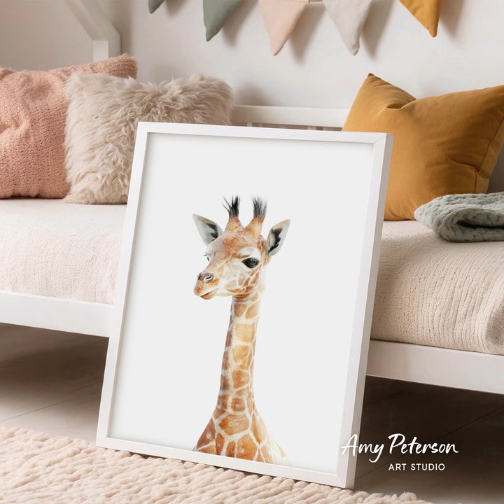 A framed print of a giraffe is displayed on a white wall in a cozy living space, with a beige couch and colorful pillows in the background.