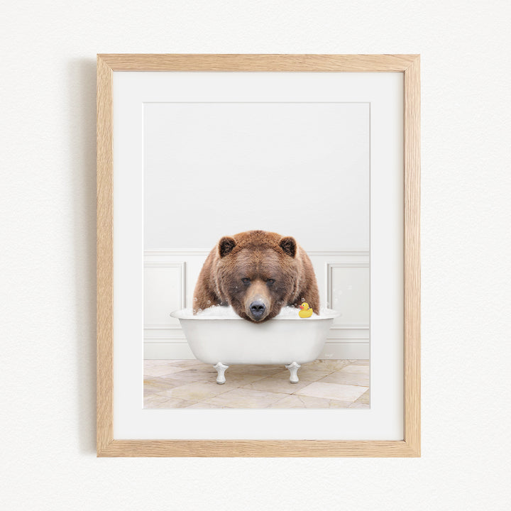 A brown bear is sitting in a white bathtub, surrounded by a yellow rubber duck.