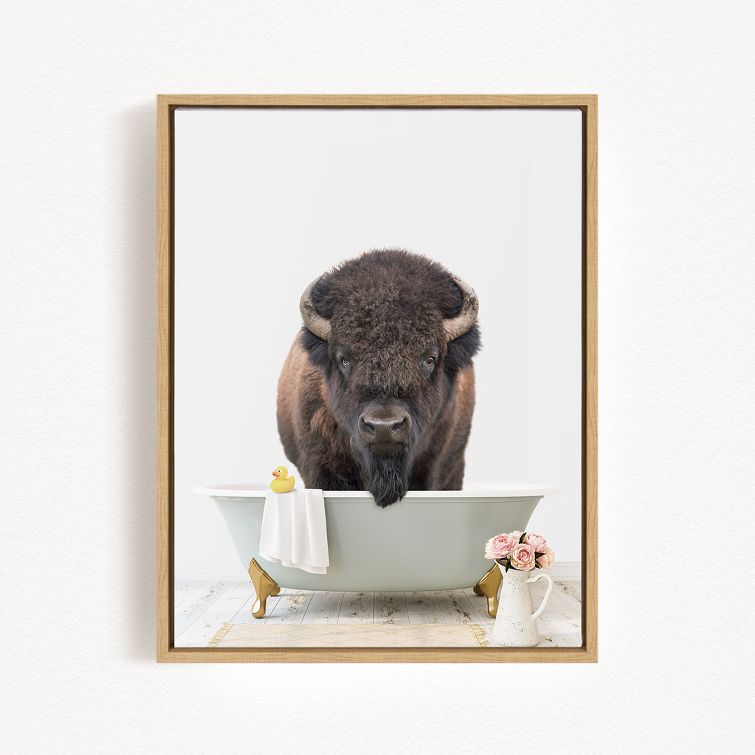 A buffalo standing in a bathtub, with a yellow rubber duck and pink flowers nearby.