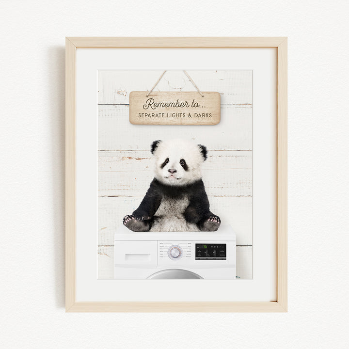 A panda bear sitting on a white washing machine, with a wooden sign above that reads "Remember to separate lights & darks".